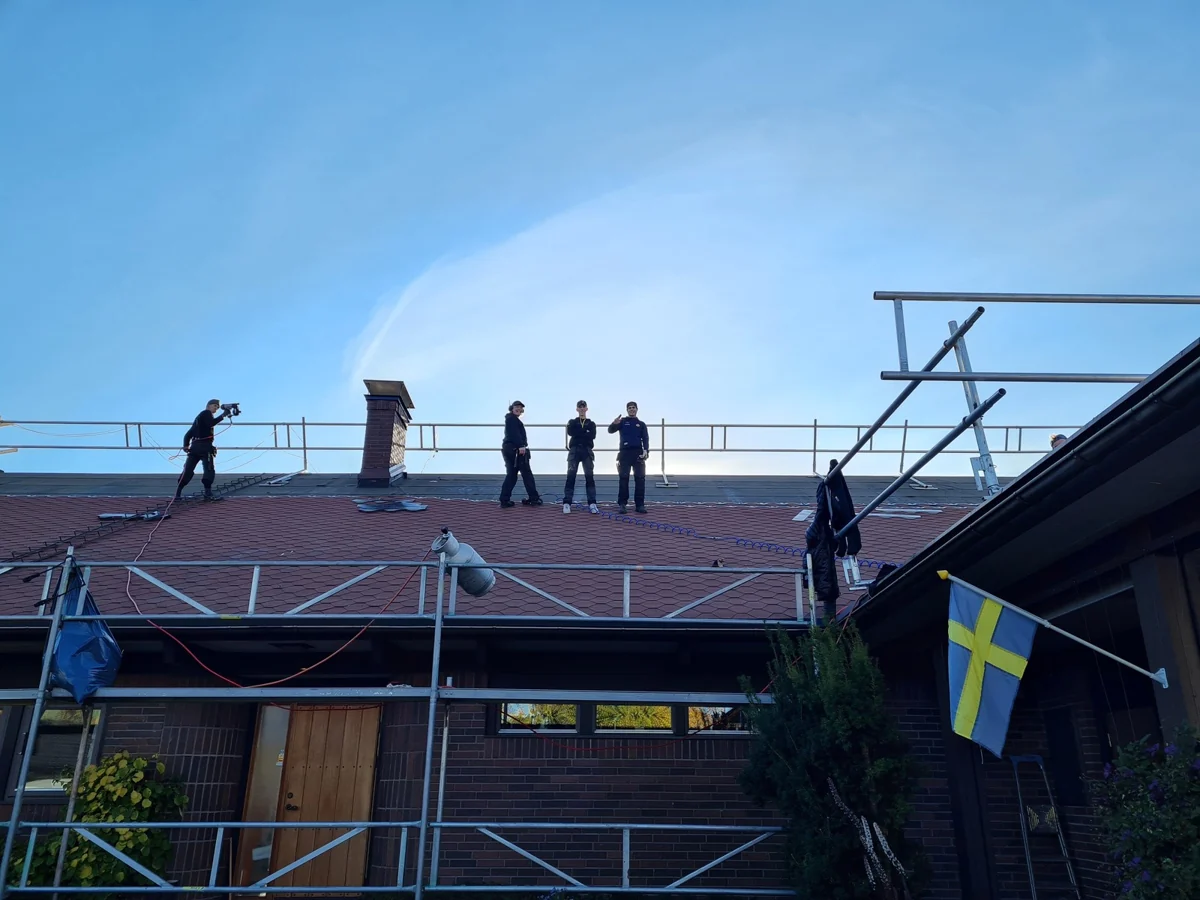 Takläggare i arbete på ett hus med röda takpannor, från företagets bildarkiv.